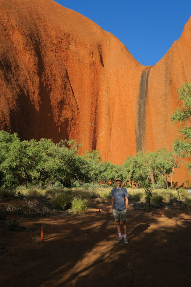 Male traveller stood by Uluru
