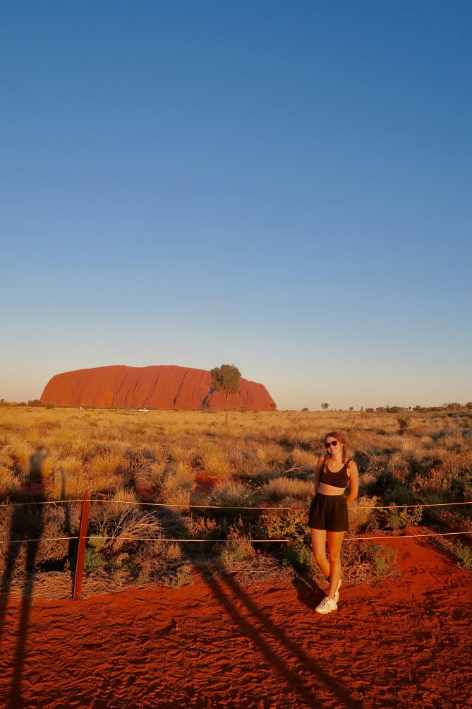 Traveller stood in front of Uluru also known as Ayers rock