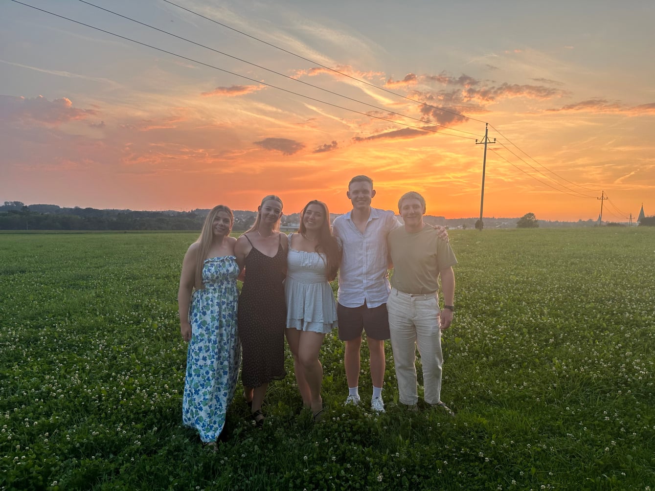 Group of travellers smiling together in the Austrian Alps during sunset