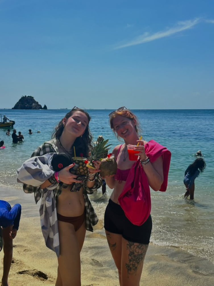 Two backpackers with coconuts on the beach