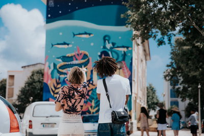 Two travellers admiring a mural on the side of a building