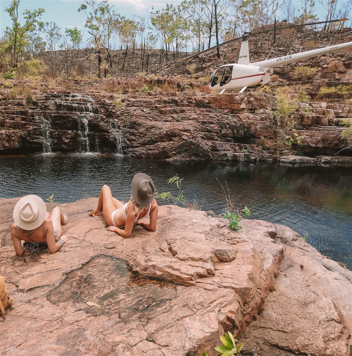People sat near Sandy Creek and helicopter at Sandy Creek in Northern Territory