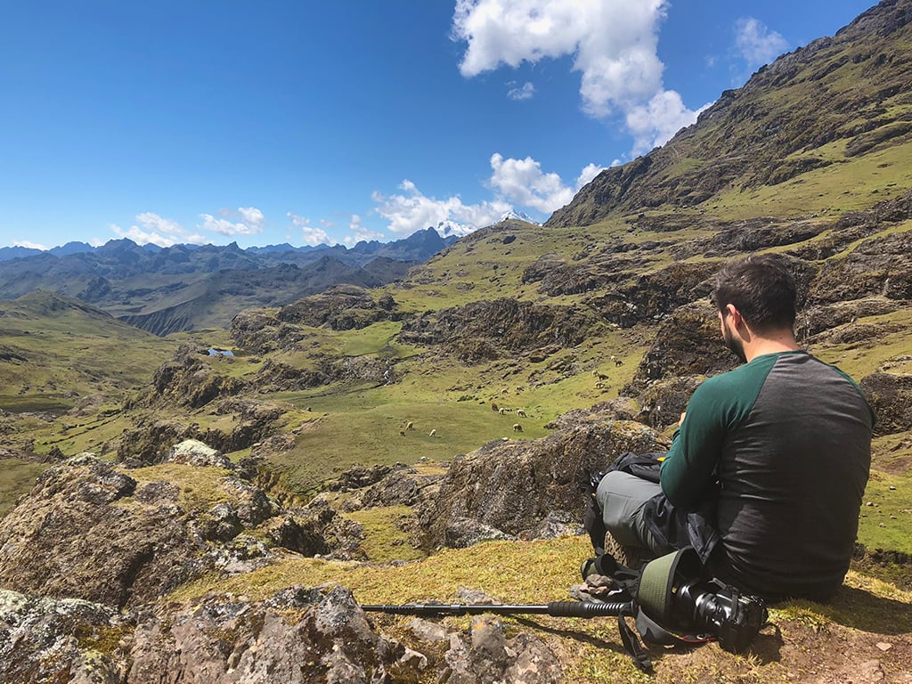 A traveller sitting on a rock overlooking mountains