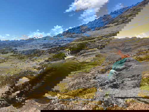 A traveller sitting on a rock overlooking mountains