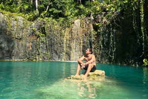 Traveller sat on a rock at a cenote in Mexico