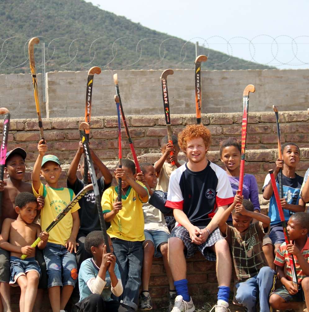 Coach sports in South Africa - group of kids with hockey sticks raised in the air