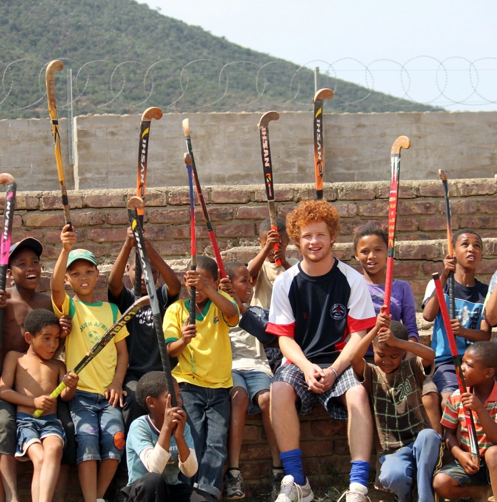 Coach sports in South Africa - group of kids with hockey sticks raised in the air