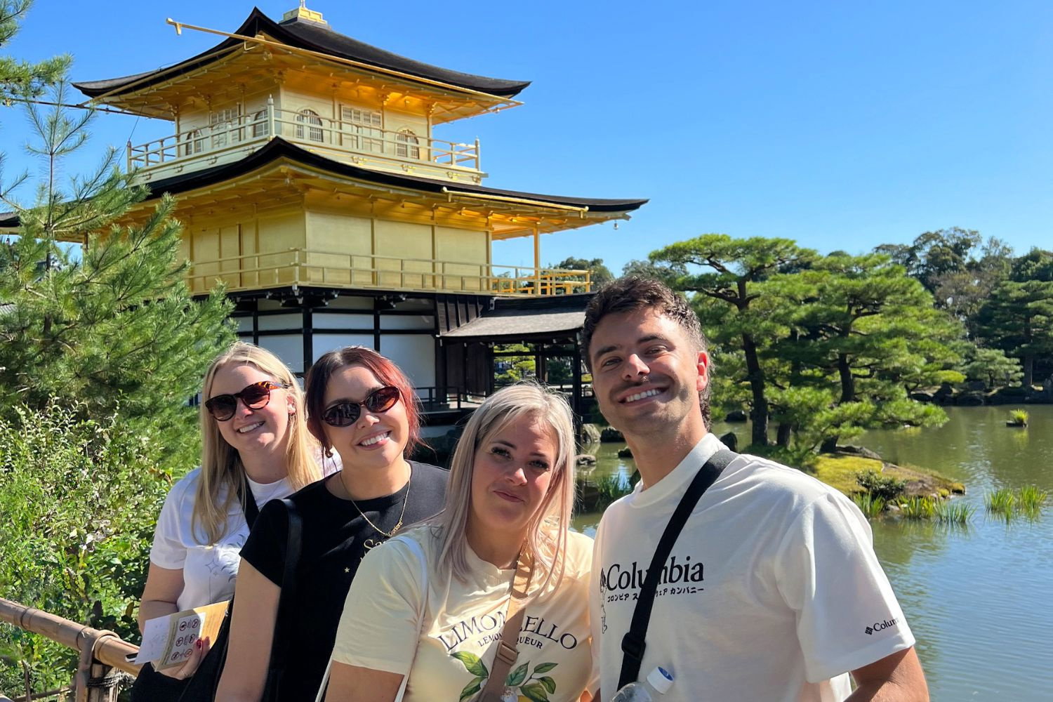 Travellers smiling by the Golden Pavilion in Kyoto