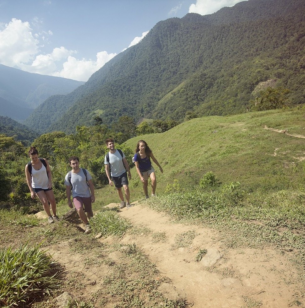 Lost City Trek Colombia. 4 travellers in shorts walking in remote mountainous green area
