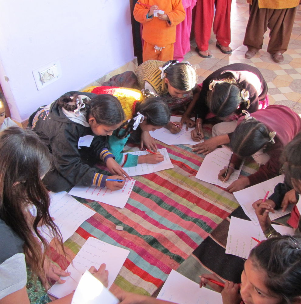 Schoolchildren on the floor writing on paper