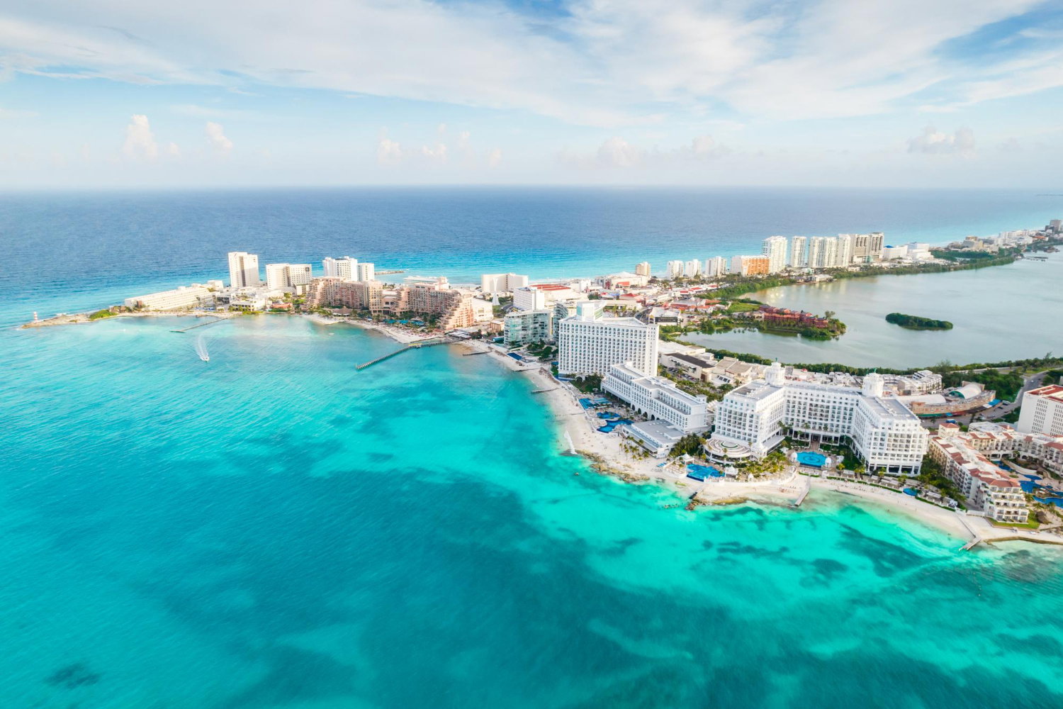 Aerial shot of resort skyscraper hotels by white stretches of sand all around the island with bright turquoise ocean, Cancun