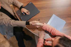 Two people at a desk shaking hands