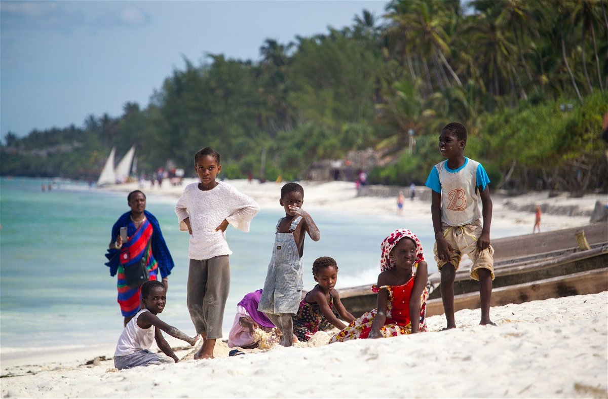 kids on a white sand beach in zanzibar with palm trees in the background