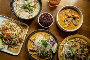 A table full of various Thai dishes, including noodle dishes and soups