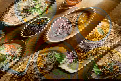 A table full of various Thai dishes, including noodle dishes and soups