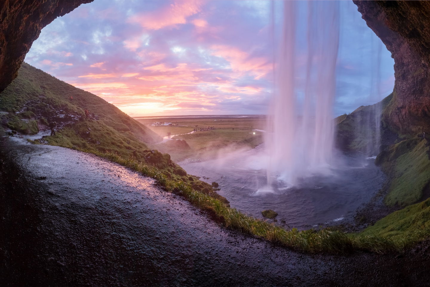 Underneath a waterfall with pink sky