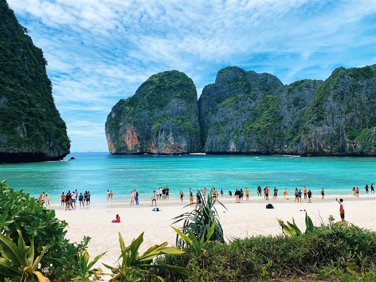 A beach in Phuket with white sand, blue water, and islands in the background