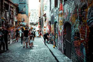 People walking down a busy lane plastered with street art in Melbourne