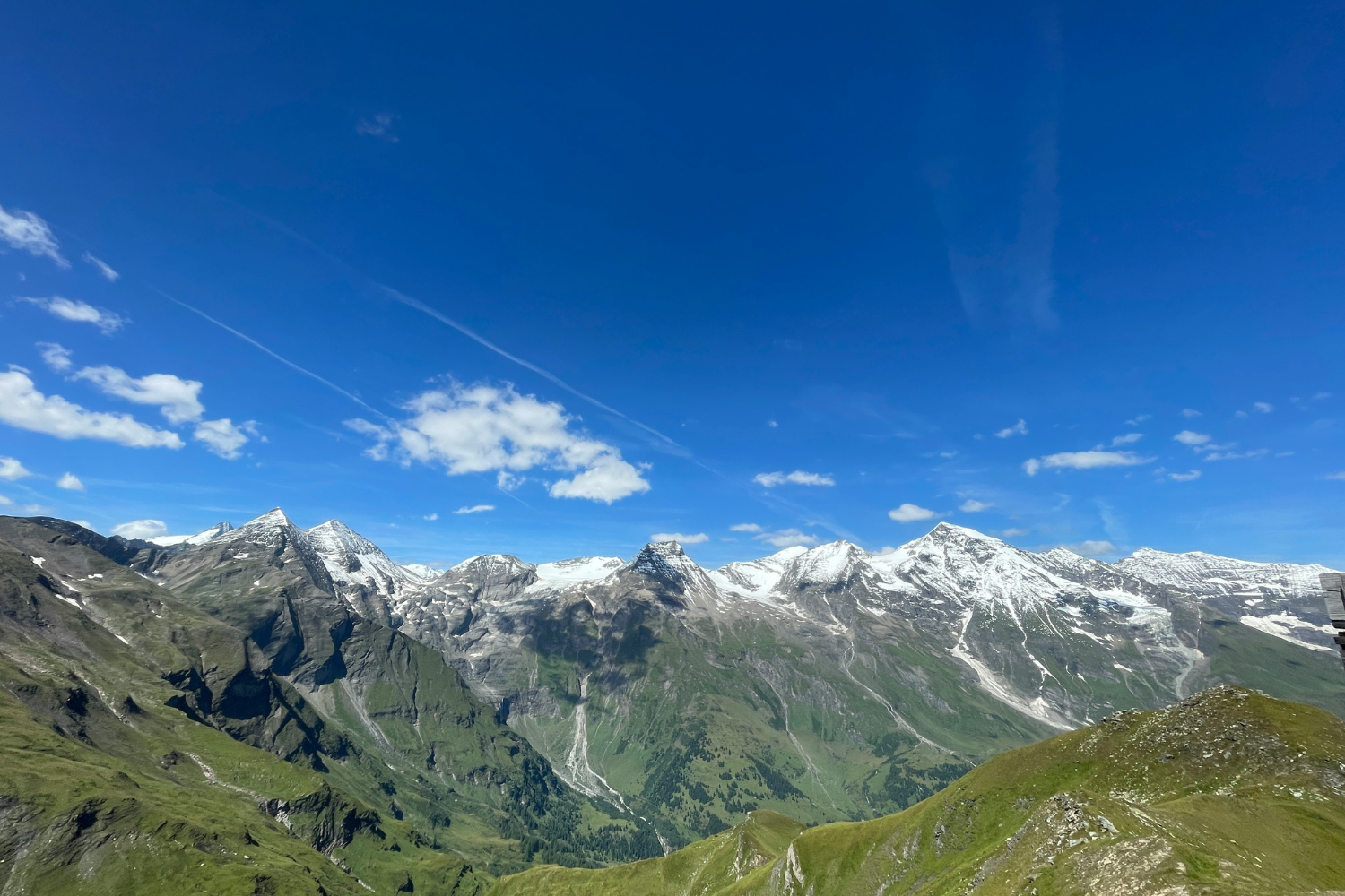 The Austrian Alps in the summer, with green mountains and snowy mountain tops, and blue skies
