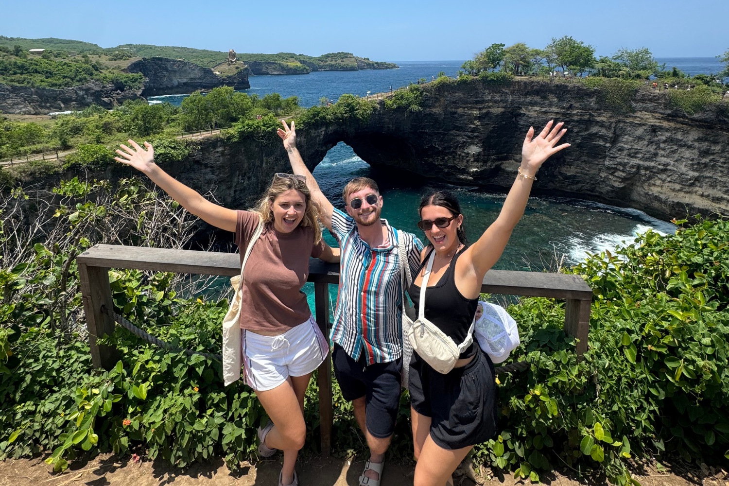 Travellers with arms at the air at Broken Beach on Nusa Penida in Bali