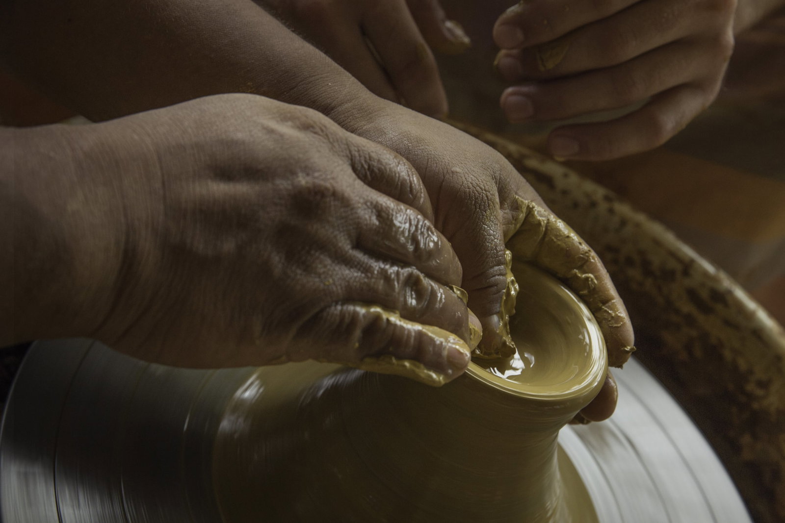 Hands working clay on a pottery wheel