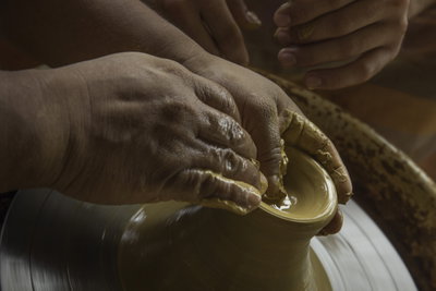 Hands working clay on a pottery wheel