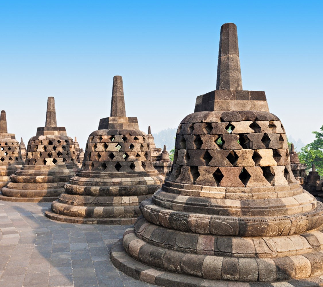 Bell-shaped grey domes on stone floor at top of temple with blue skies