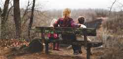A person sitting on a bench with two children