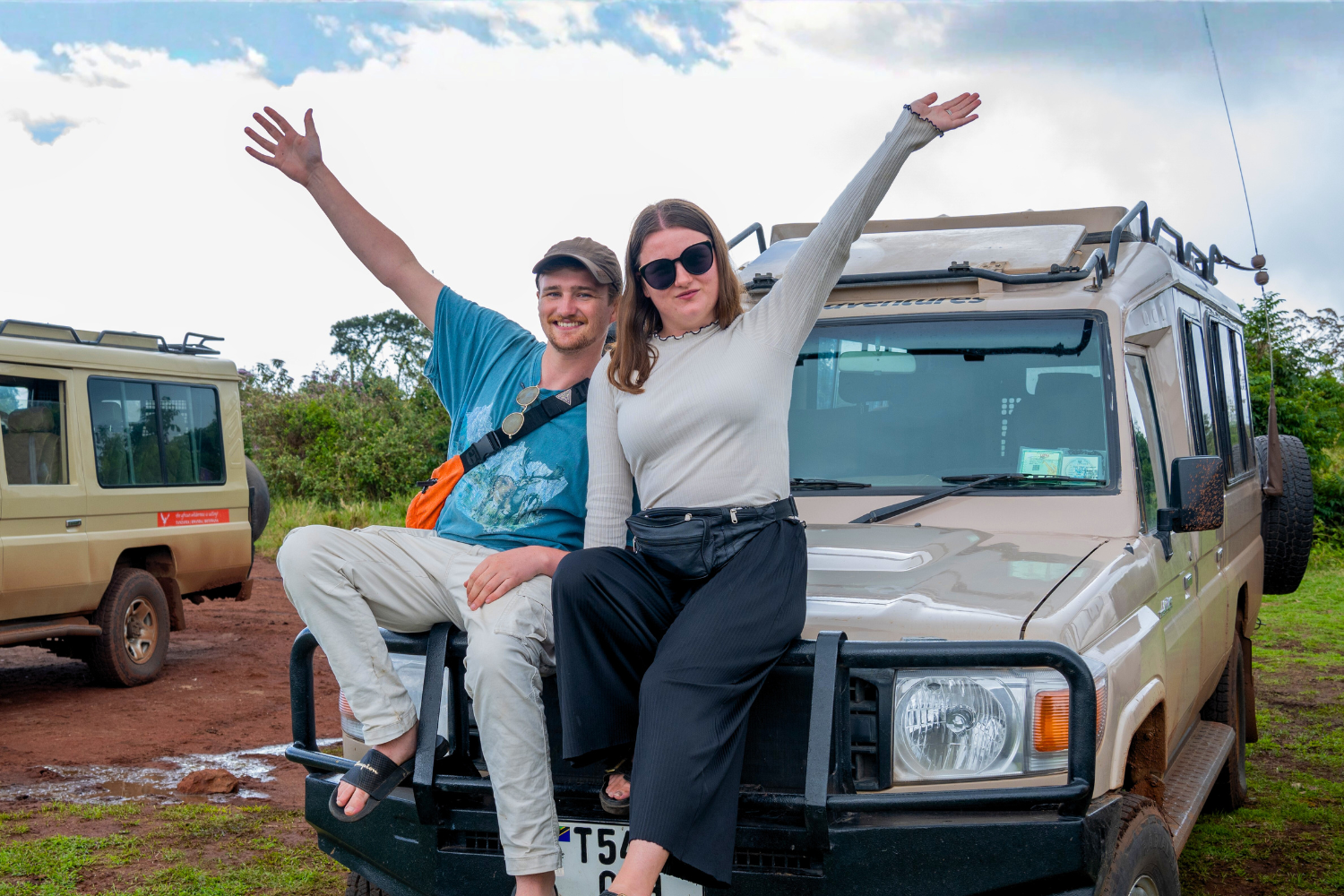 Two travellers on a group trip in Tanzania in front of a safari jeep
