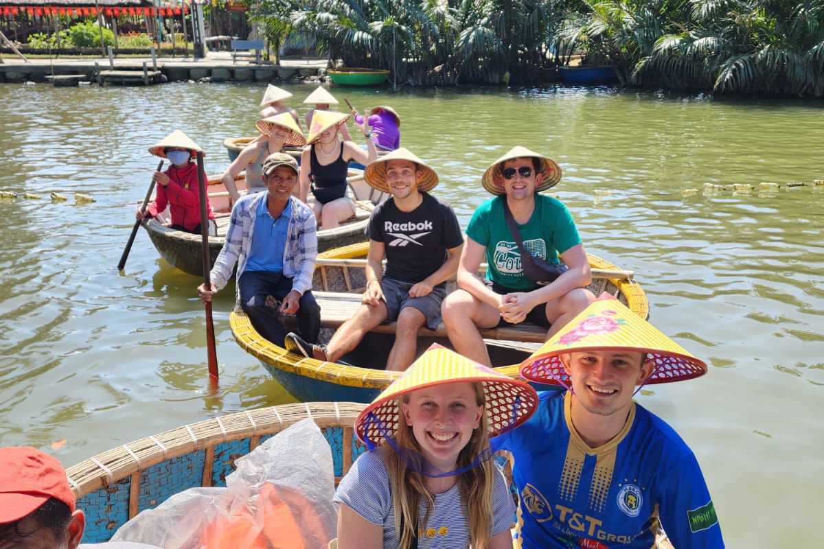 Group of travellers wearing vietnamese hats in boats on river