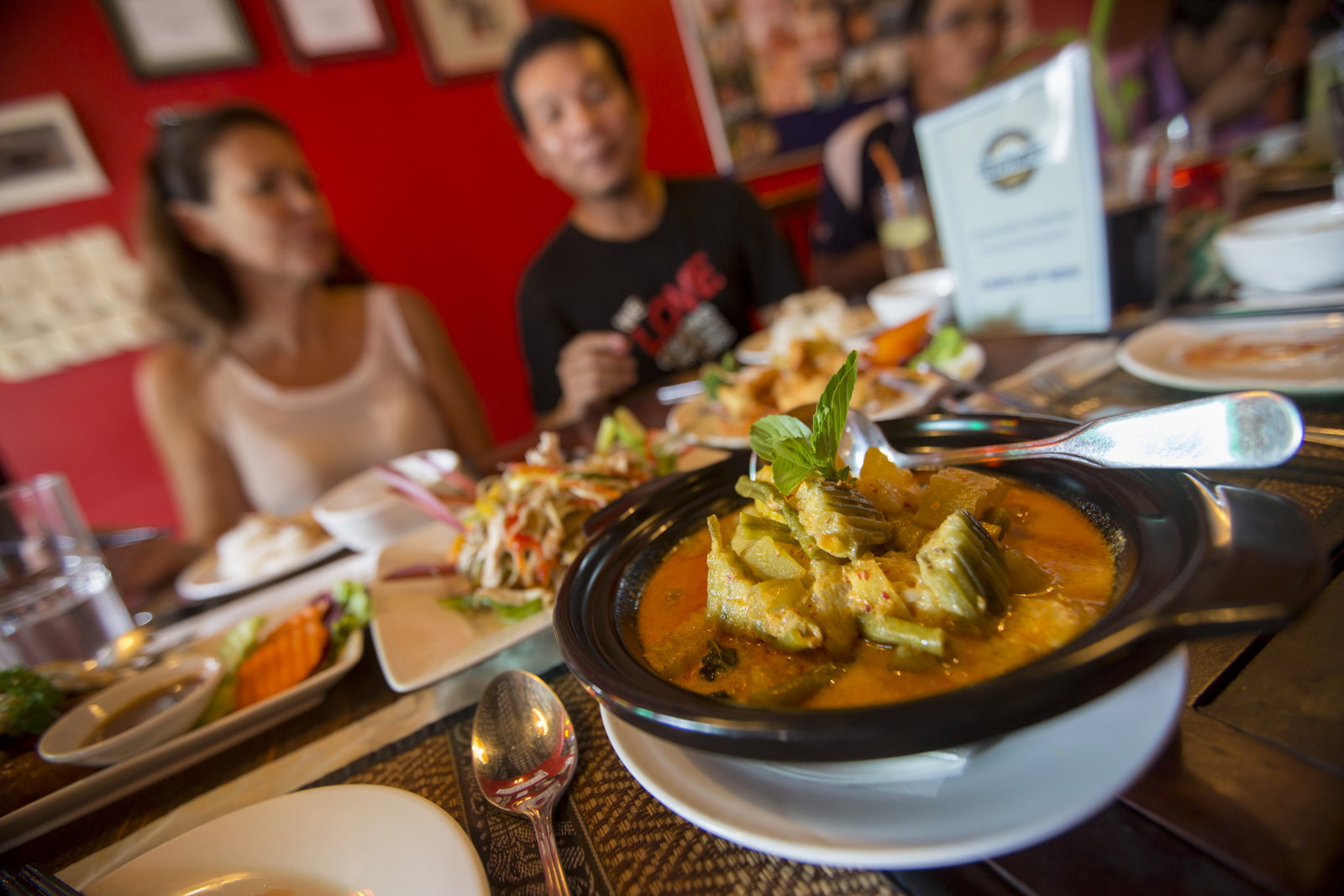 Two people sit at a table full of traditional Cambodian food