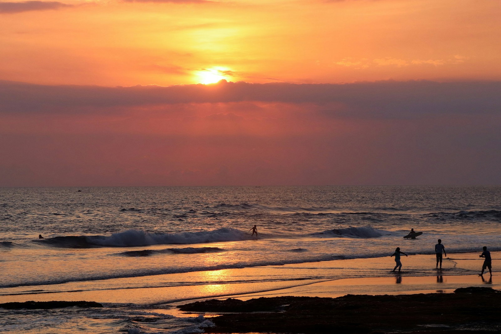 Beach at sunset with surfers riding the waves, Bali