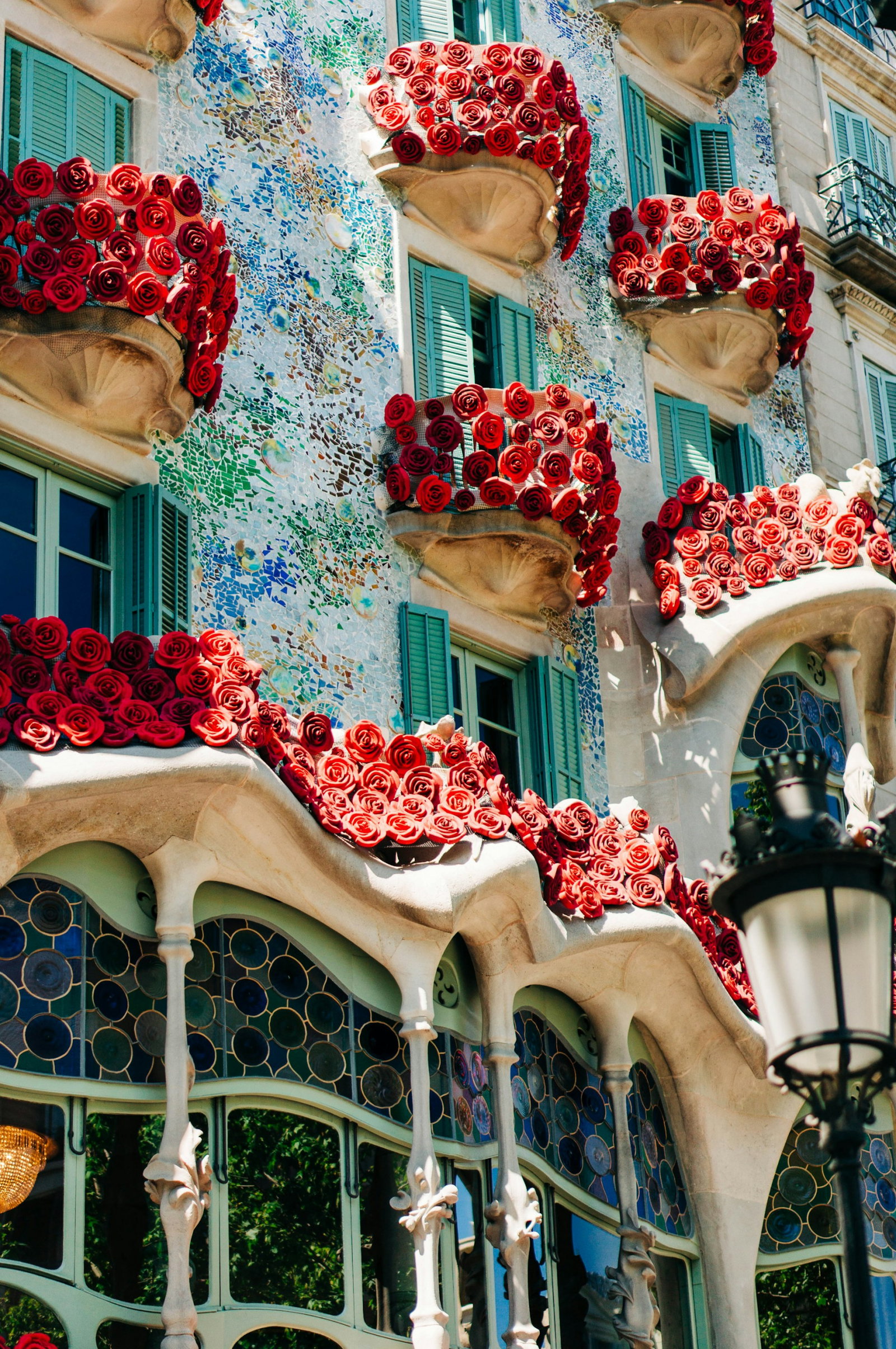 Famous Gaudi architecture with balconies and roses on bright blue building in Barcelona