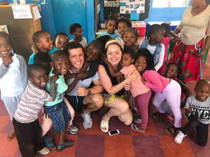 Two travellers with a group of smiling schoolchildren