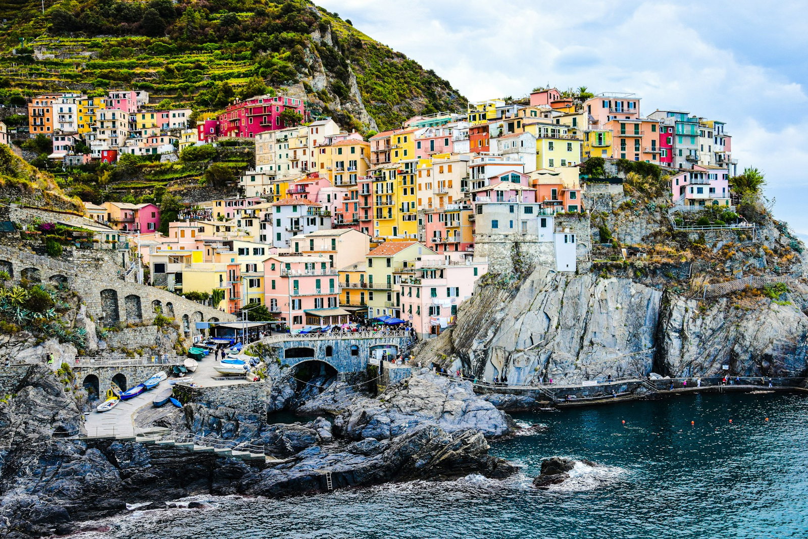 Rainbow coloured fishing buildings nestled into the cliffs and cascading farmlands with boats close to the centre