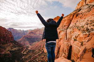 Traveller with arms up in rocky mountains