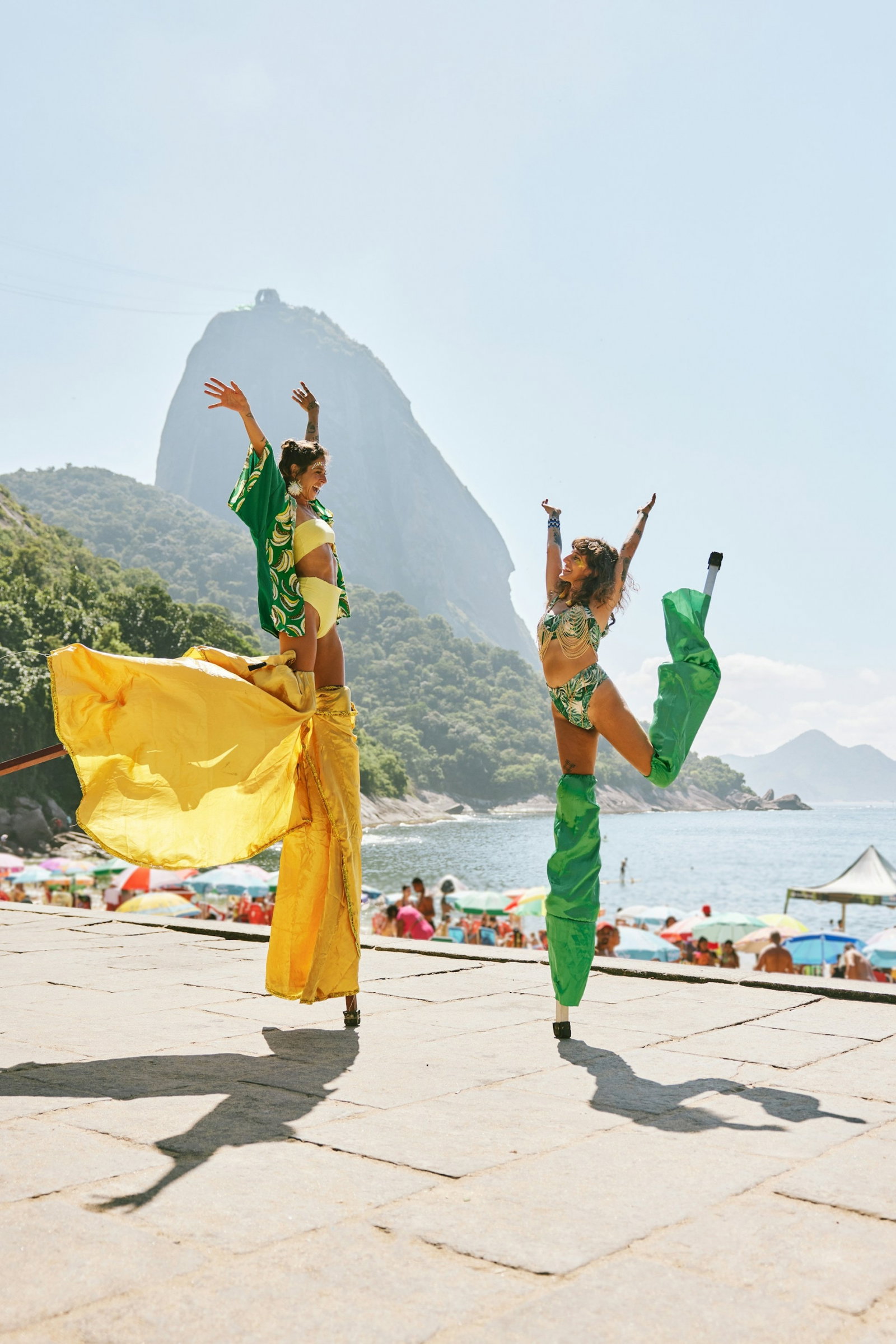 Dancers on stilts and in traditional Carnival costumes by beach with rainforest