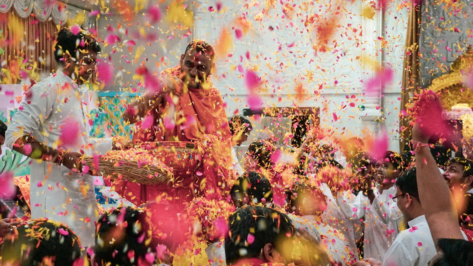 Holi celebrations with pink and yellow confetti and crowd dressed in traditional dress