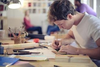 A person in a classroom writing in a book