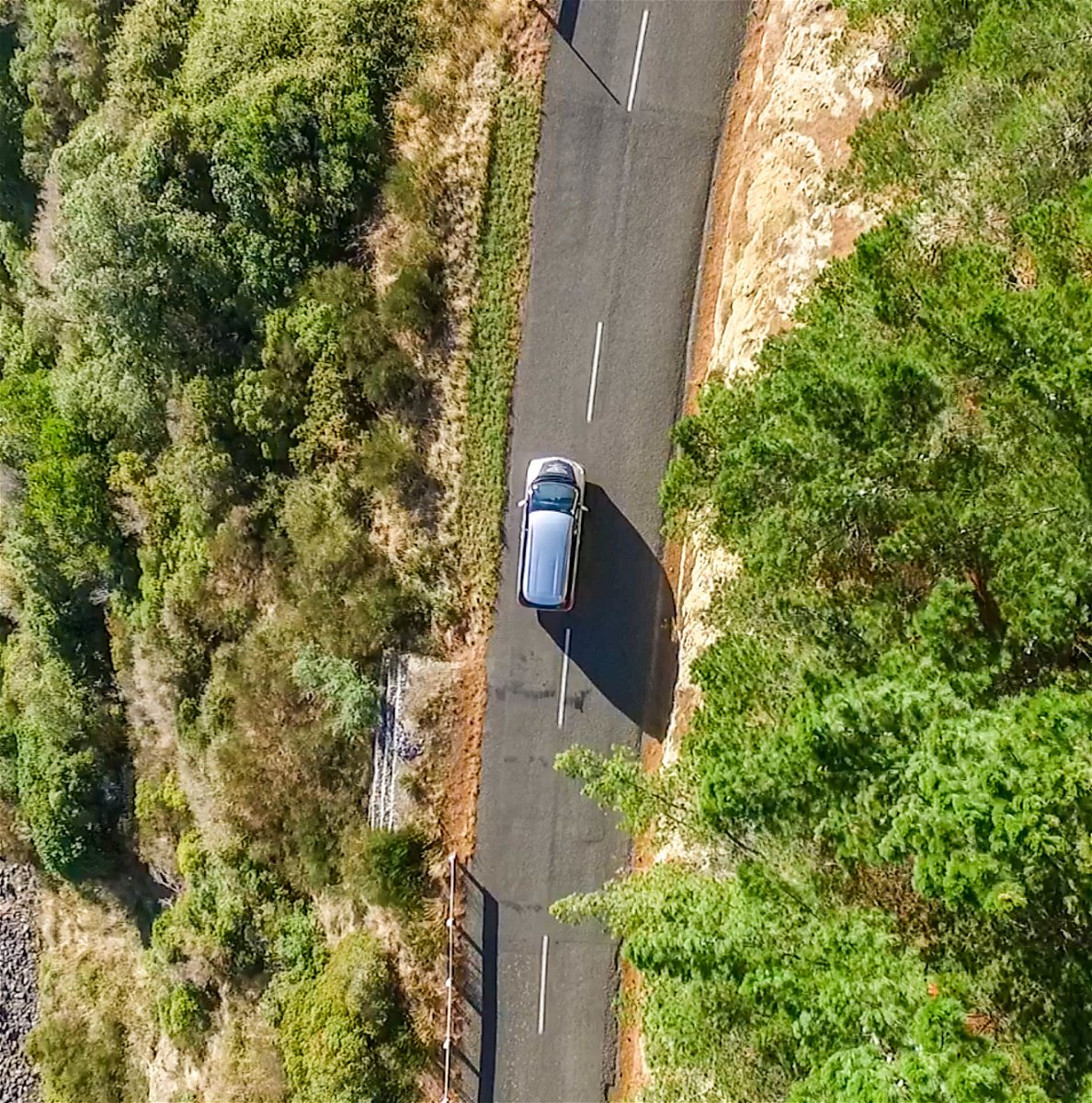 Epic road trips in New Zealand. Drone photo of car driving along road near the coast