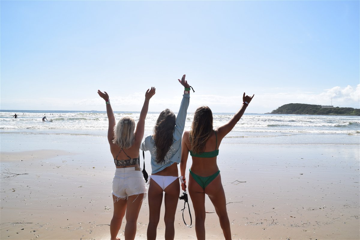 Travellers with hands up in the air on beach in Australia 