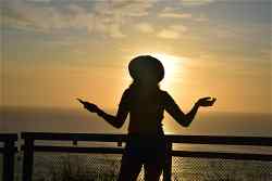 Female traveler silhouette laughing against sunset