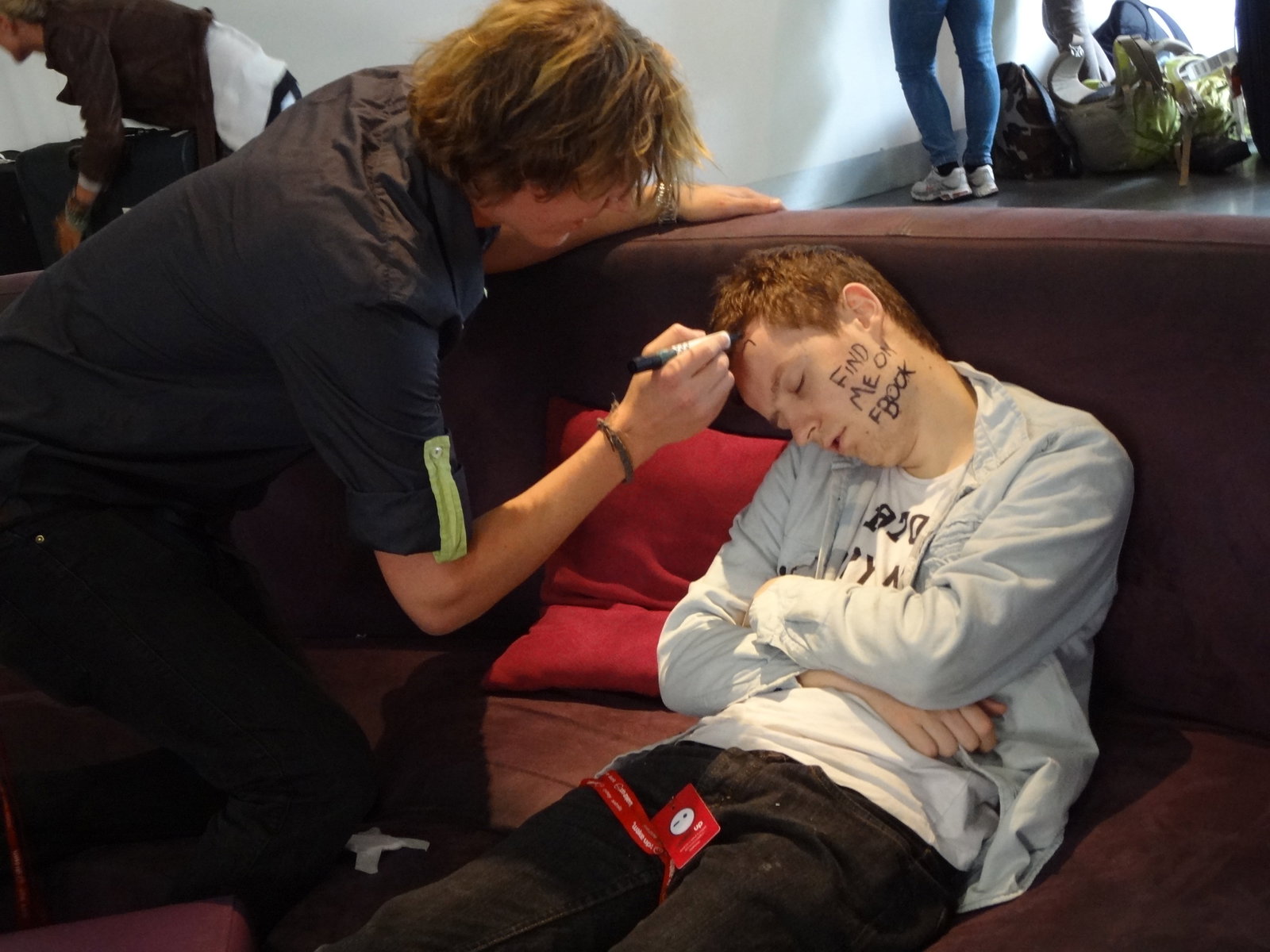 A traveller drawing on another travellers face while they sleep