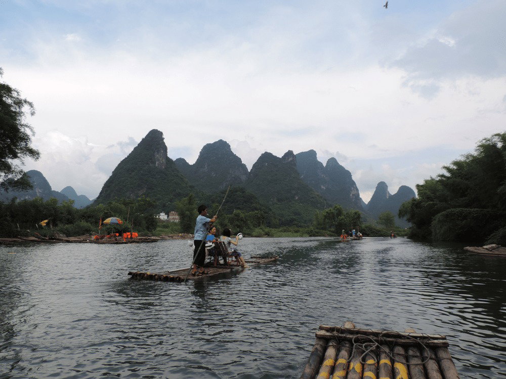 People travelling down a river on wooden rafts