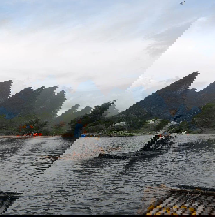 People travelling down a river on wooden rafts