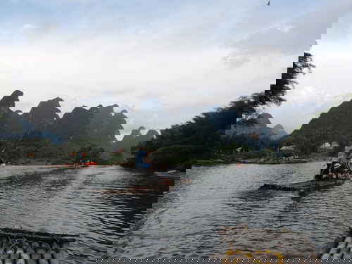 People travelling down a river on wooden rafts