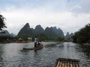 People travelling down a river on wooden rafts