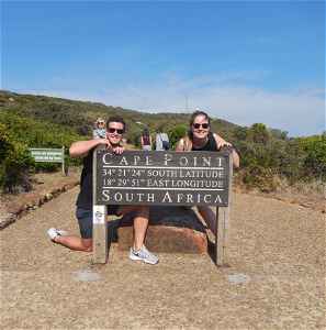 Two people behind Cape Point sign in Cape Town, South Africa 