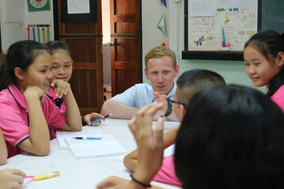 Teacher kneeling down to engage with students in a classroom