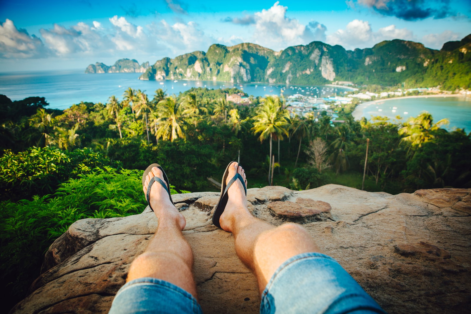 Traveller sitting on a rock overlooking jungle, ocean and surrounding islands